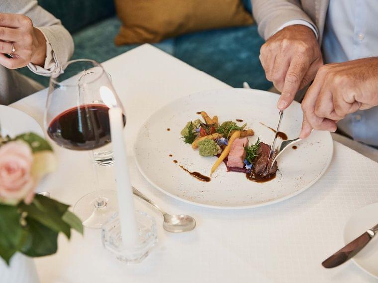Elegant fine dining dish with vegetables and meat served with red wine