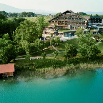 Luxury lakeside hotel surrounded by forest and mountains with a private dock on turquoise water