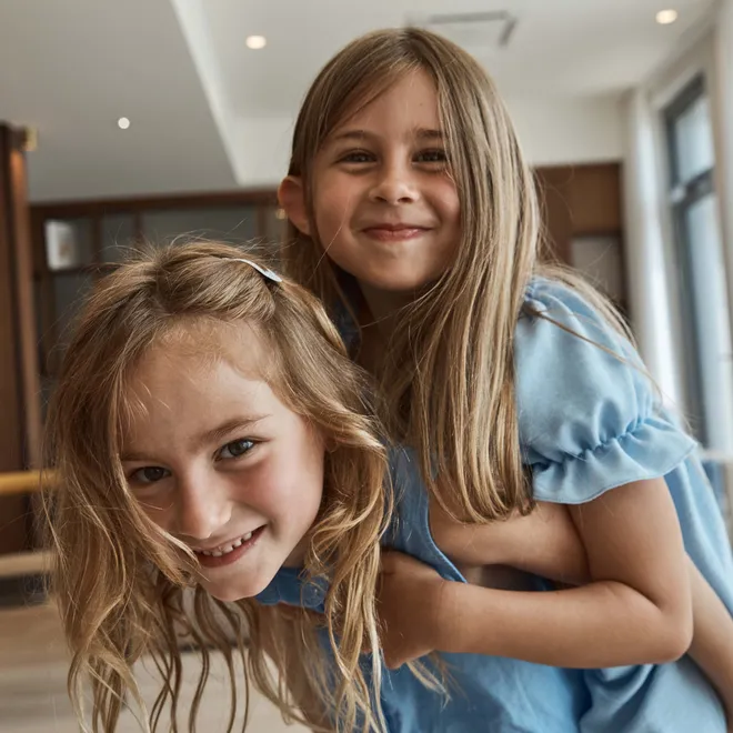 Smiling sisters playing together indoors in natural light