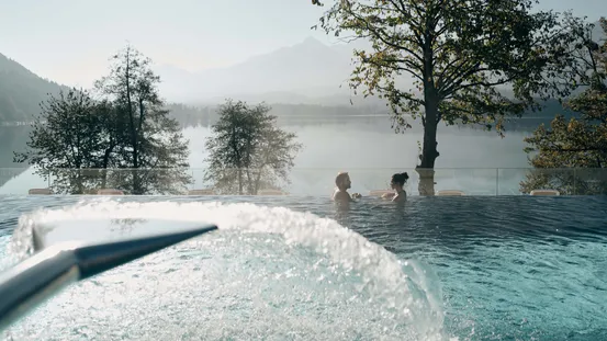 Paar entspannt im Infinity-Außenpool mit Blick auf See und Berge
