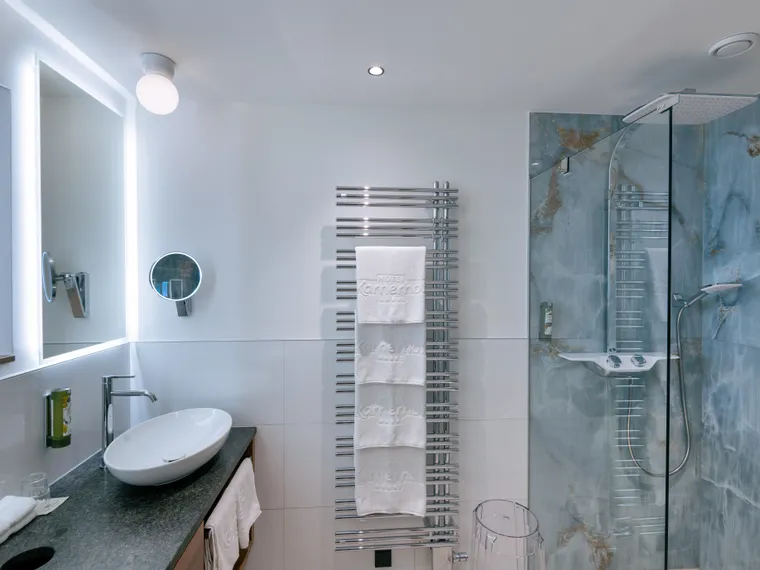 Modernes Hotelbadezimmer mit Aufsatzwaschbecken, Handtuchwärmer und Glasdusche