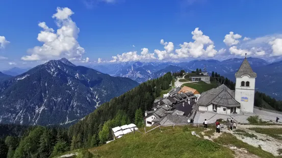 Malerdorf in den Alpen mit Kirchturm und Panoramablick unter blauem Himmel