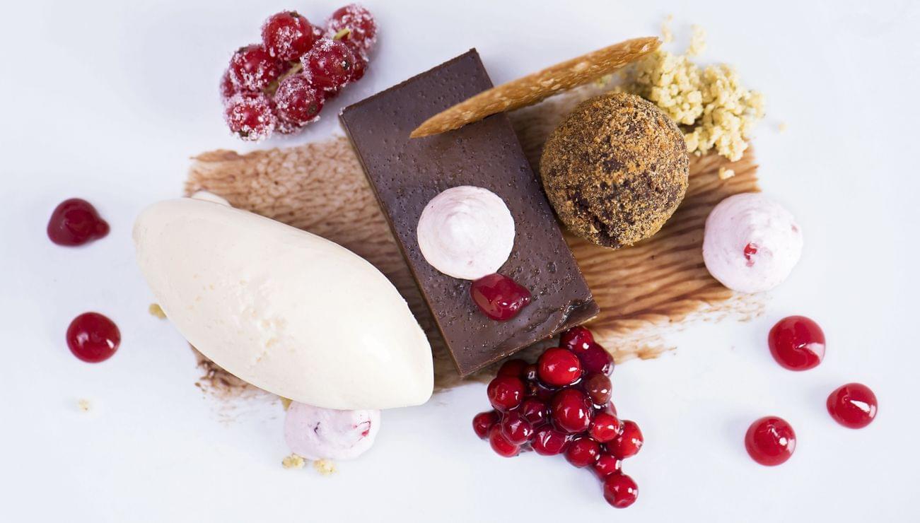 Dessert gourmet al cioccolato con gelato, ribes rosso, mousse e guarnizione di crumble