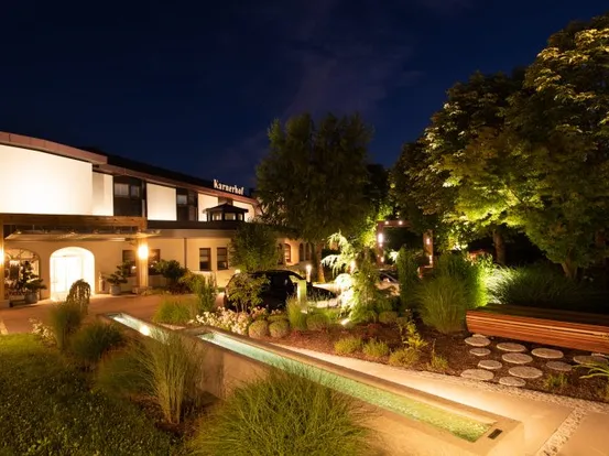 Luxuriöse Hotelfassade mit Garten und Wasserbecken bei Nacht beleuchtet