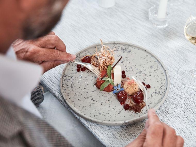 Gourmet dessert with cherries, mousse and edible flowers on speckled plate
