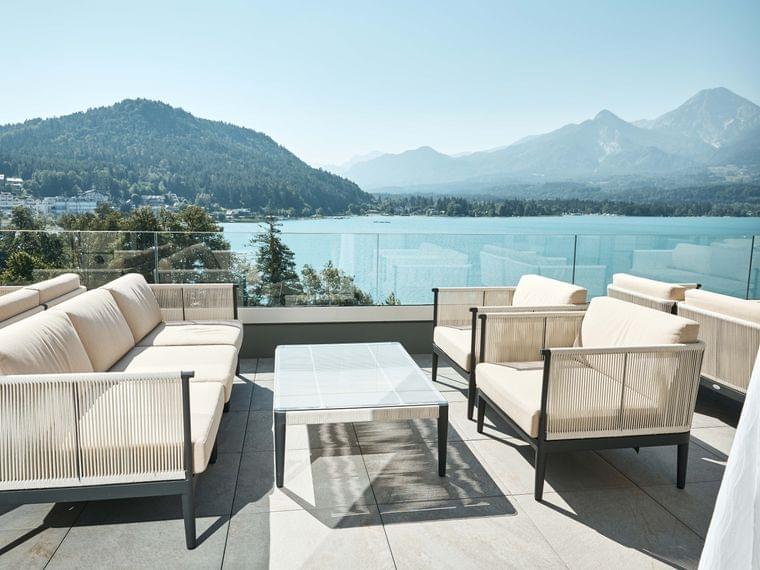 Salotto esterno moderno con mobili beige vista lago e montagne