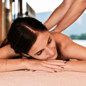 Entspannte Frau erhält Rückenmassage im Spa mit Bergblick