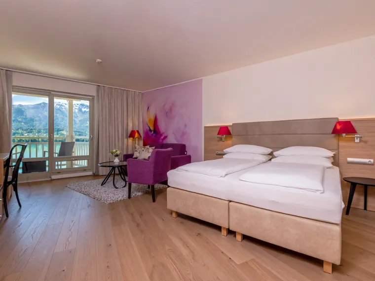 Modernes Hotelzimmer mit Doppelbett, lila Stühlen und Bergblick