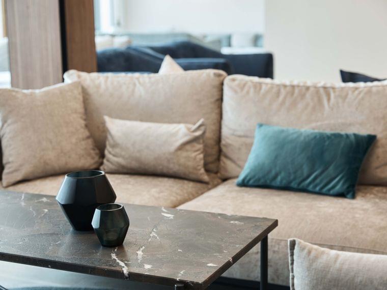 Modern beige sofa with velvet cushions and black geometric vases on a marble coffee table
