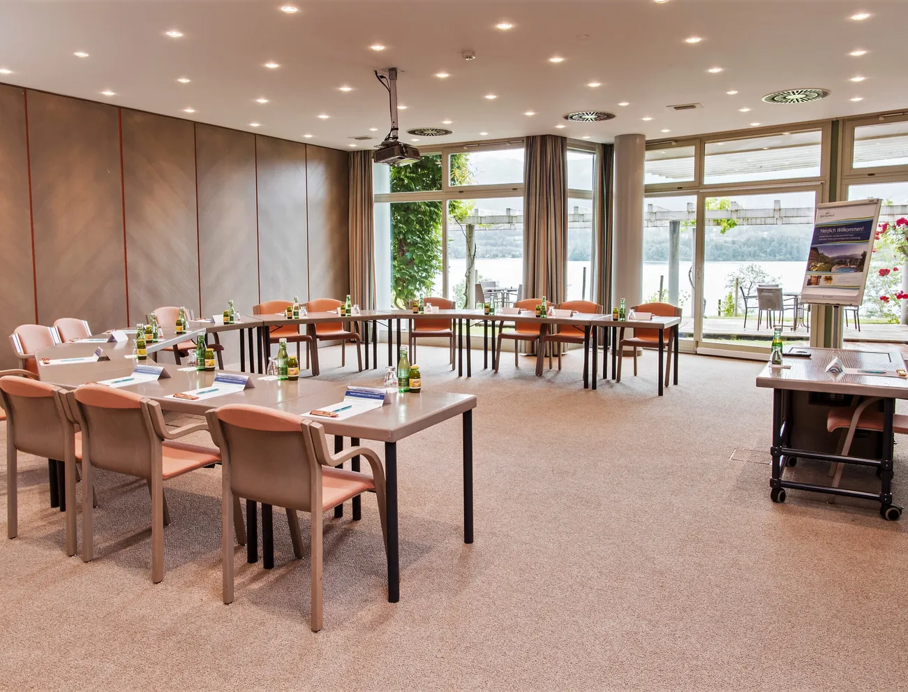 Moderner Konferenzraum mit U-förmiger Tischanordnung und Seeblick durch große Fenster