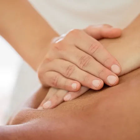 Therapeut führt eine Tiefengewebsmassage am Rücken einer Person durch