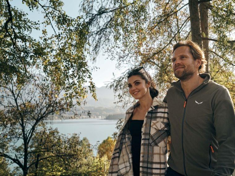 Couple walking in autumn forest with lake and mountains in the background