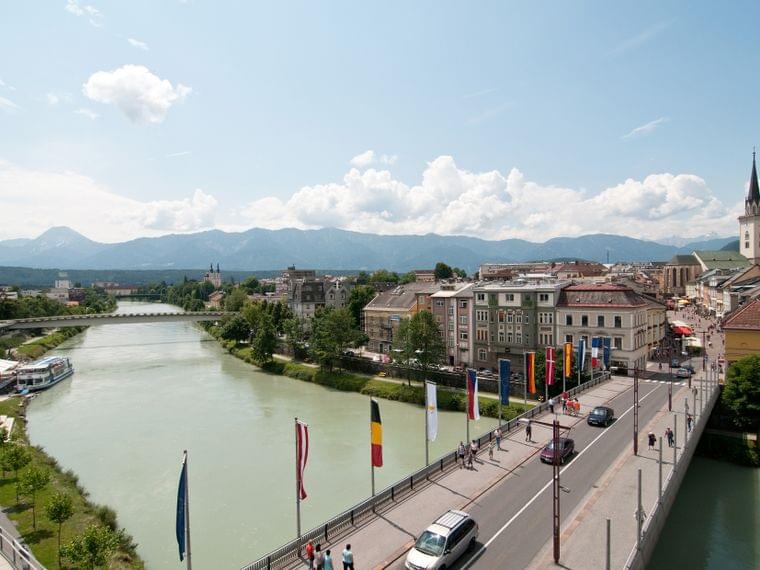 Bridge over the river in Villach with colorful buildings and mountain backdrop