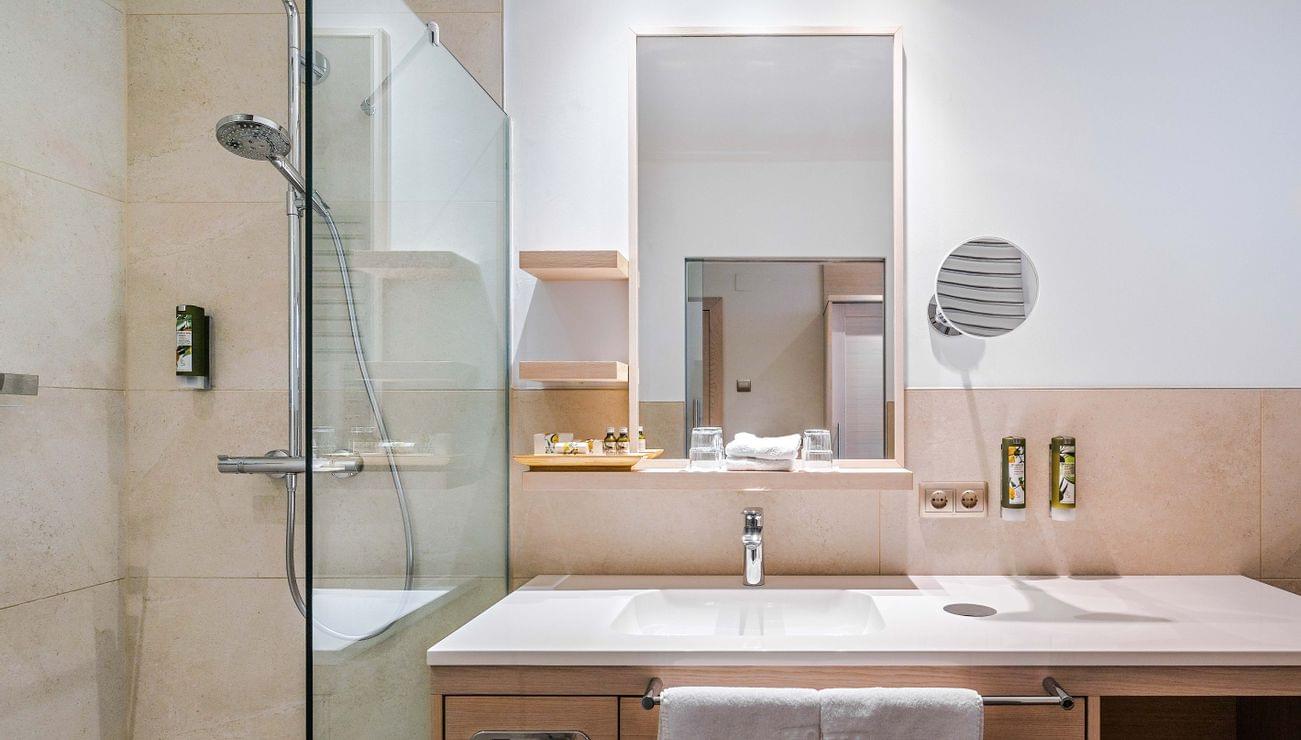 Bagno d'hotel moderno con doccia walk-in, grande specchio e articoli da toeletta ordinati