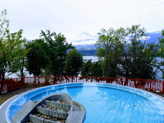 Runder Brunnen mit Steinen mit Blick auf einen See und nebelbedeckten Berg im Hintergrund