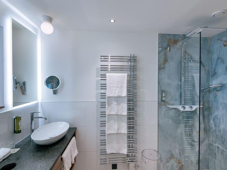 Modernes Hotelbadezimmer mit Aufsatzwaschbecken, Handtuchwärmer und Glasdusche