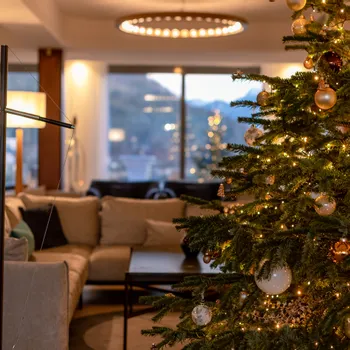 Gemütliches Wohnzimmer mit geschmücktem Weihnachtsbaum und warmem Festlicht