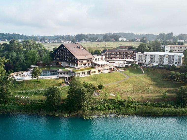 Lakeside wellness hotel surrounded by greenery with outdoor pool and countryside view