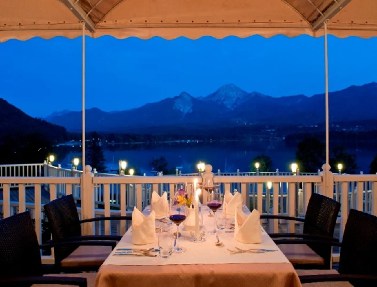 Romantisches Abendessen auf Terrasse mit Blick auf See und Berge bei Dämmerung
