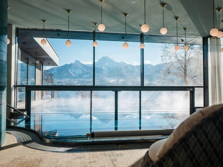 Piscina a sfioro interna con vista panoramica sulle montagne in resort spa moderno