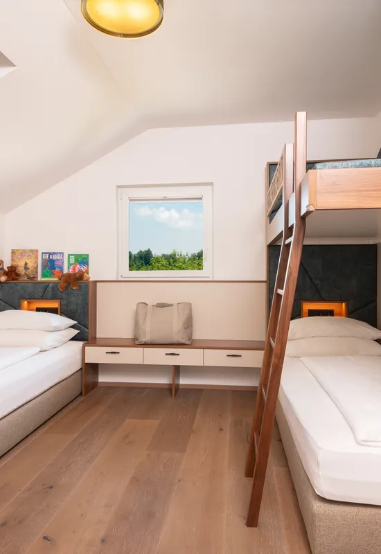 Modernes Familienzimmer mit zwei Einzelbetten und einem Etagenbett unter Dachfenster
