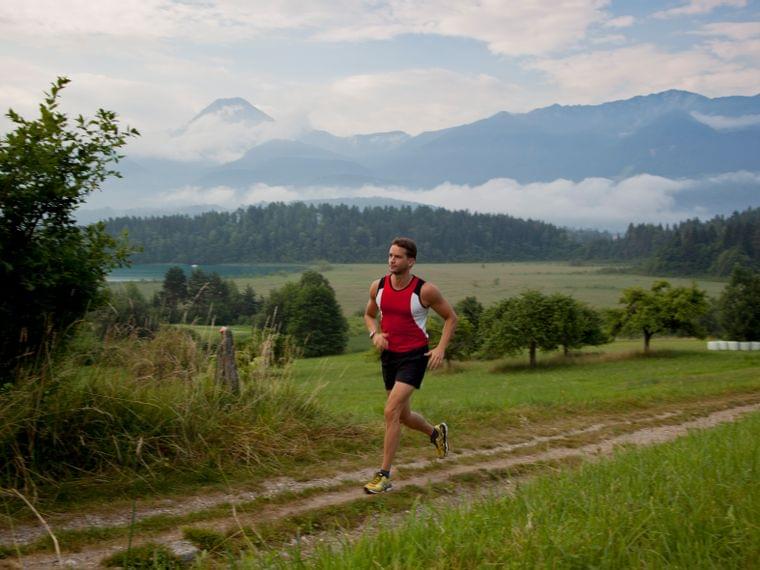 Man jogging on a rural trail with mountains and forest in the background