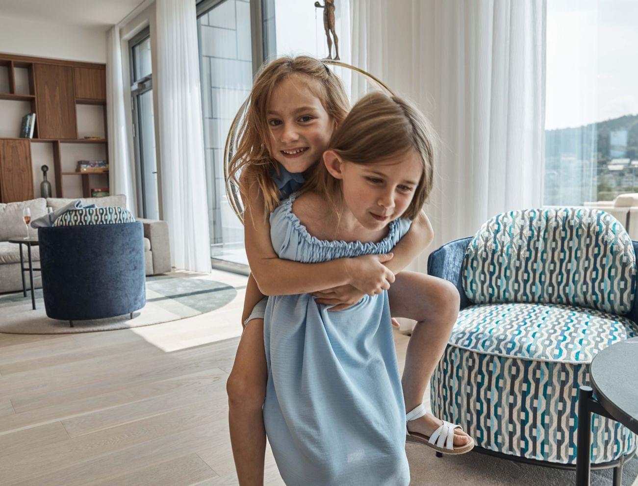 Due bambine giocano in casa, una porta l'altra sulle spalle in un soggiorno moderno