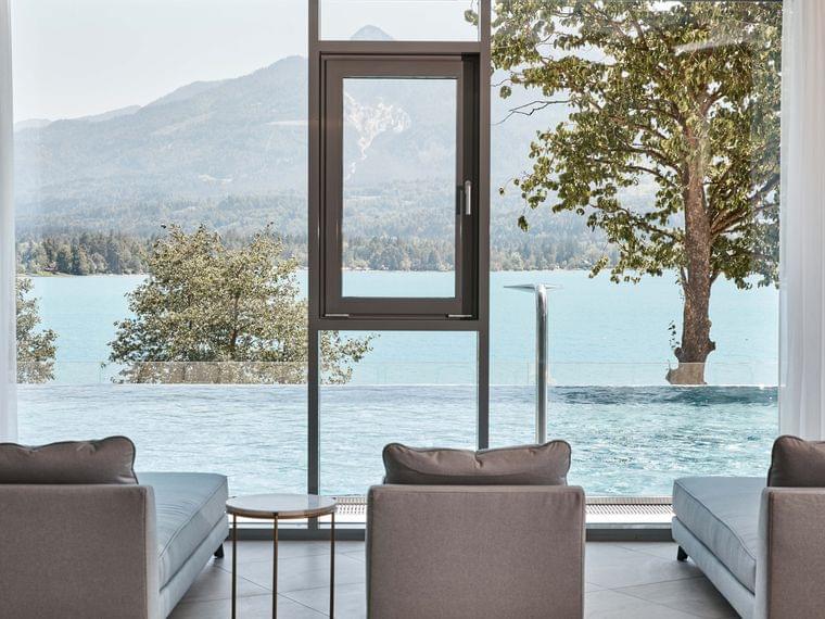 Lounge spa di lusso con vista lago, piscina a sfioro e paesaggio montano attraverso ampie finestre