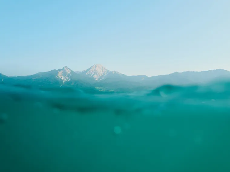 Mountain range viewed from half-submerged water under clear blue sky