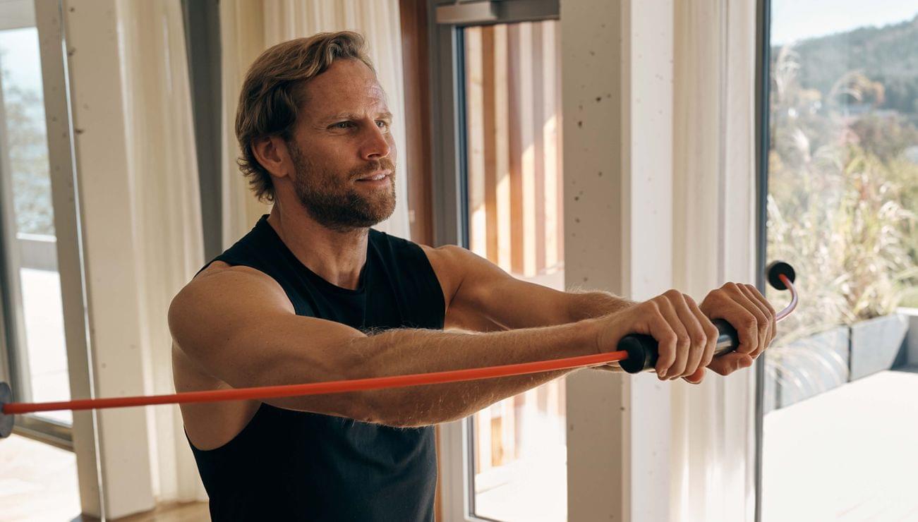 Man training indoors with resistance bar performing strength exercise