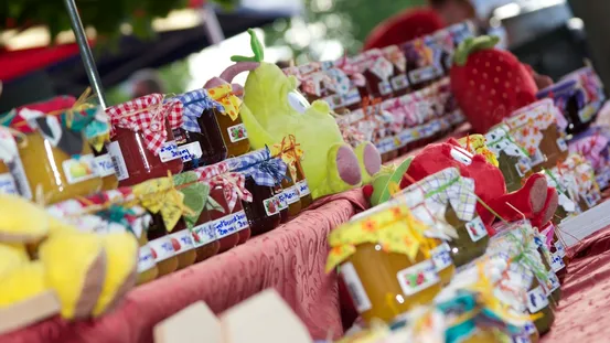 Bunte Gläser mit hausgemachter Marmelade und Stoffdeckeln auf einem Marktstand