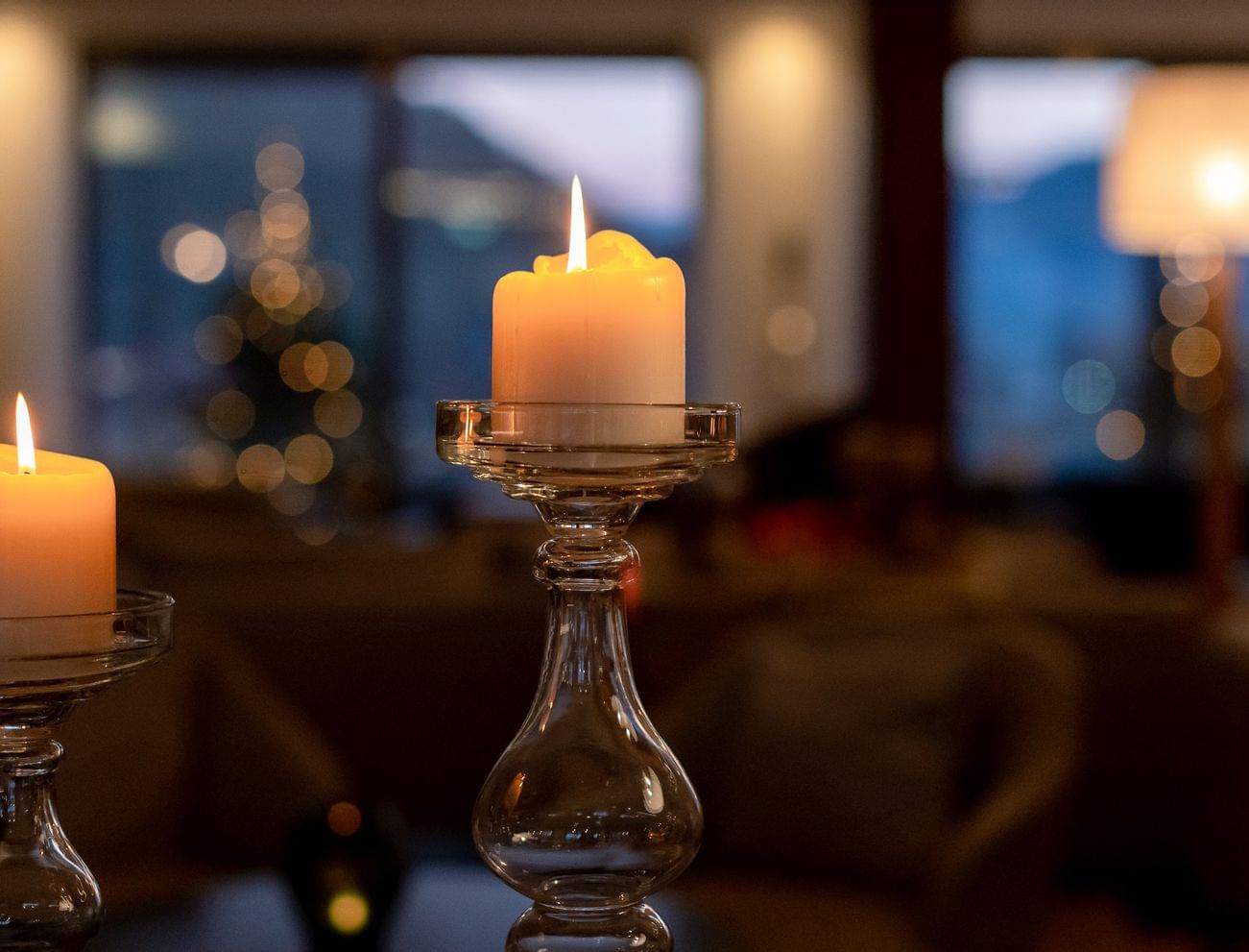 Brennende Kerzen in eleganten Glashaltern mit gemütlicher Innenraumstimmung am Abend
