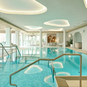 Moderna piscina coperta in hotel con lettini e illuminazione elegante