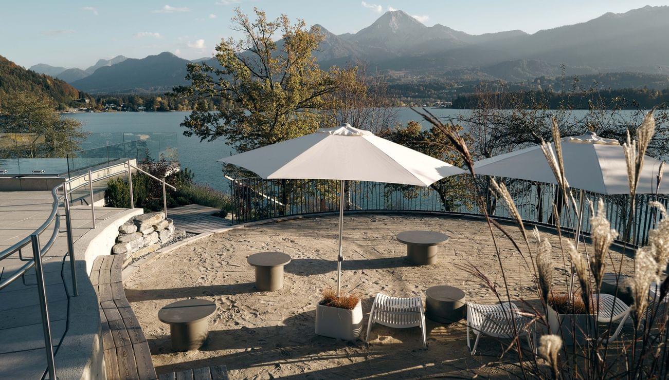 Terrazza sul lago con ombrelloni, sedie a sdraio e vista montagna in autunno