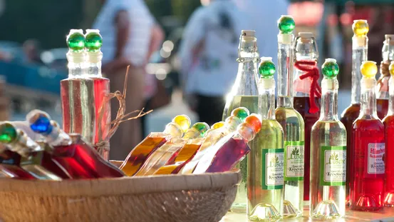 Bunte Likörflaschen mit Zierkorken auf einem Marktstand im Sonnenlicht