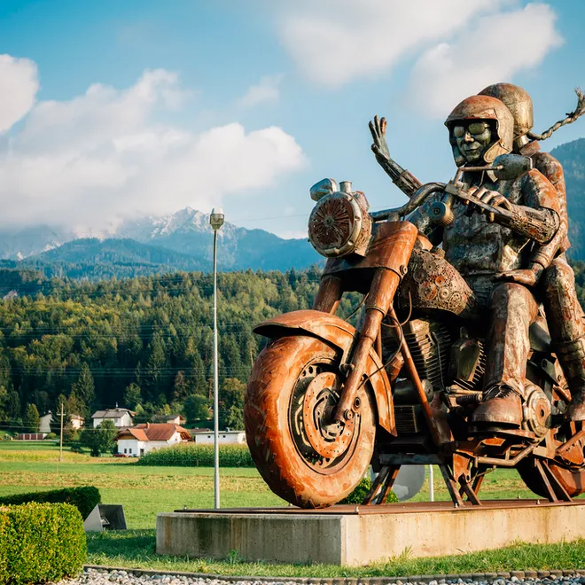 Rostige Metalls Skulptur von zwei Motorradfahrern vor Bergkulisse