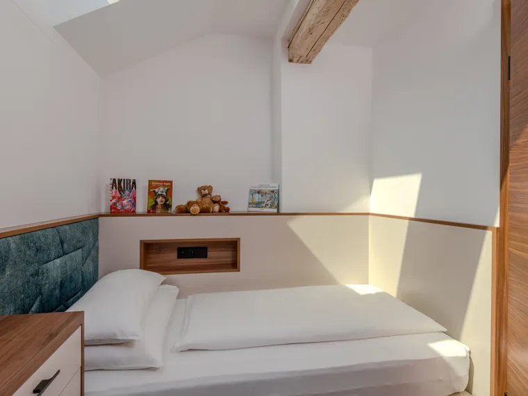 Minimalistisches Kinderzimmer mit Einzelbett, Teddybären und Büchern auf Holzregal