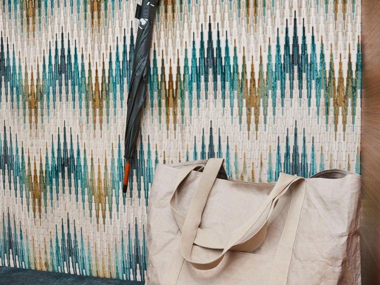 Borsa shopper in tela beige su panchina con ombrello appeso e parete decorata