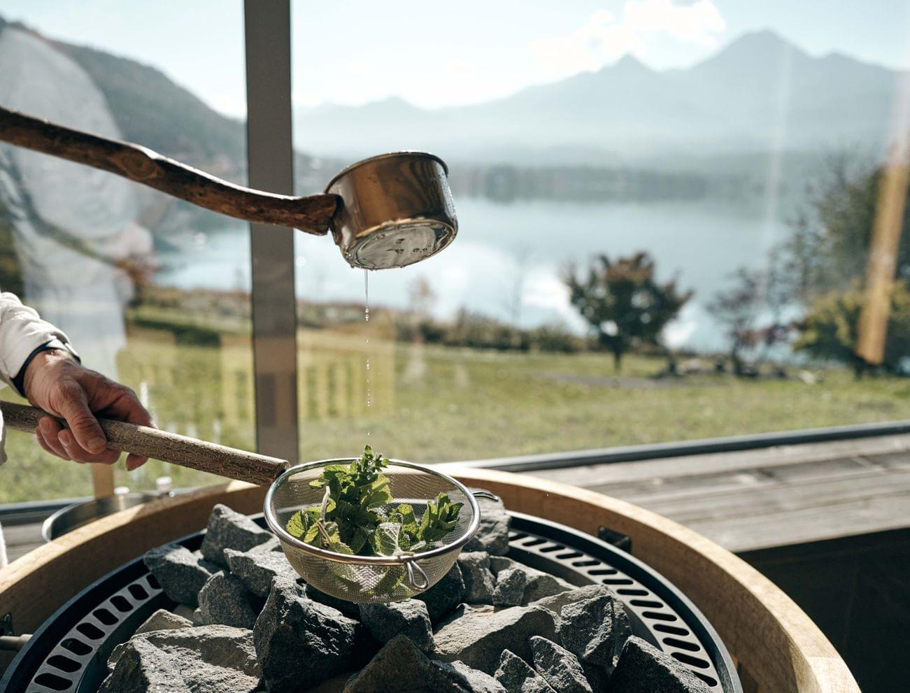 Erbe cotte al vapore su pietre calde in una sauna con vista sulle montagne