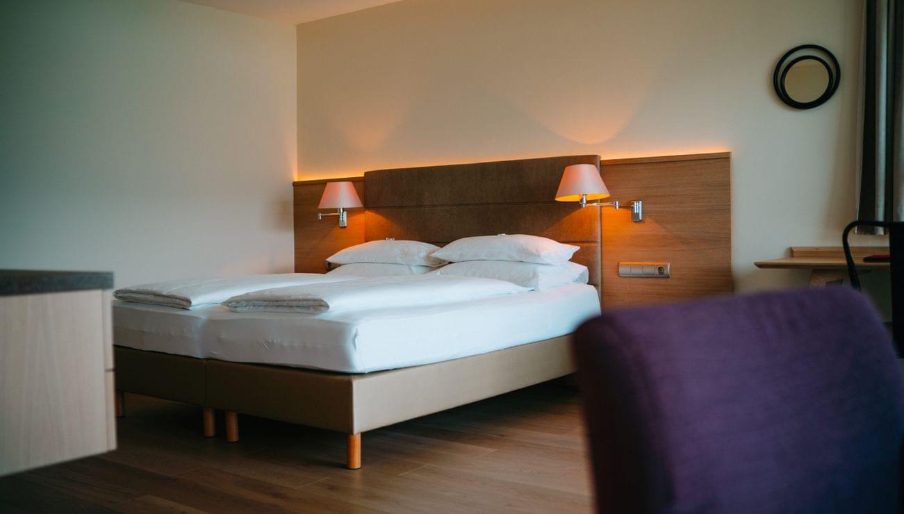 Moderna camera d'albergo con letto matrimoniale, pavimento in legno e luci soffuse
