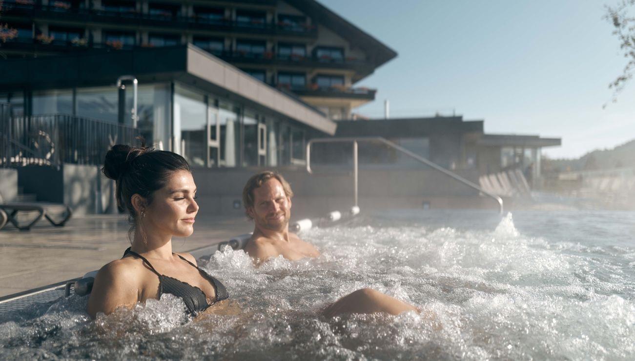 Paar entspannt im Outdoor-Whirlpool vor einem Berghotel