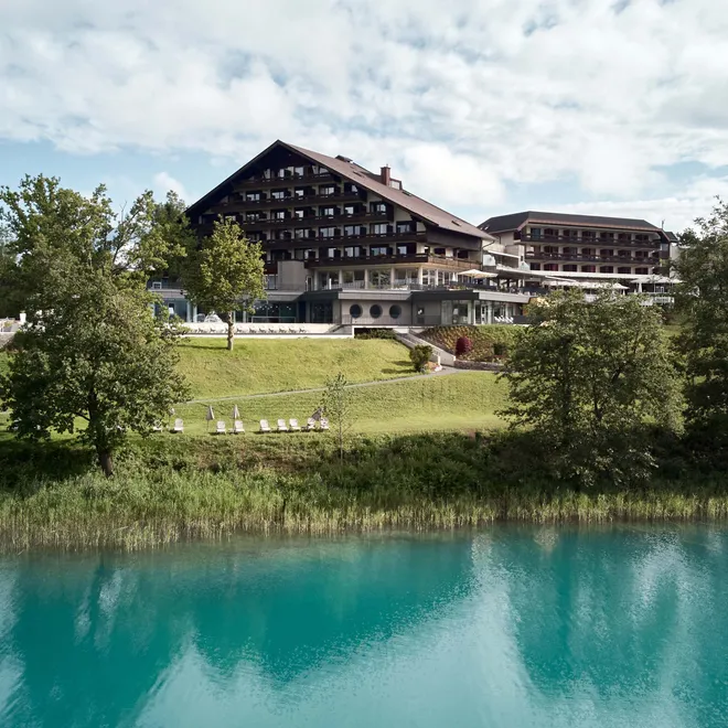 Resort benessere sul lago con edifici in stile alpino e paesaggio collinare verde