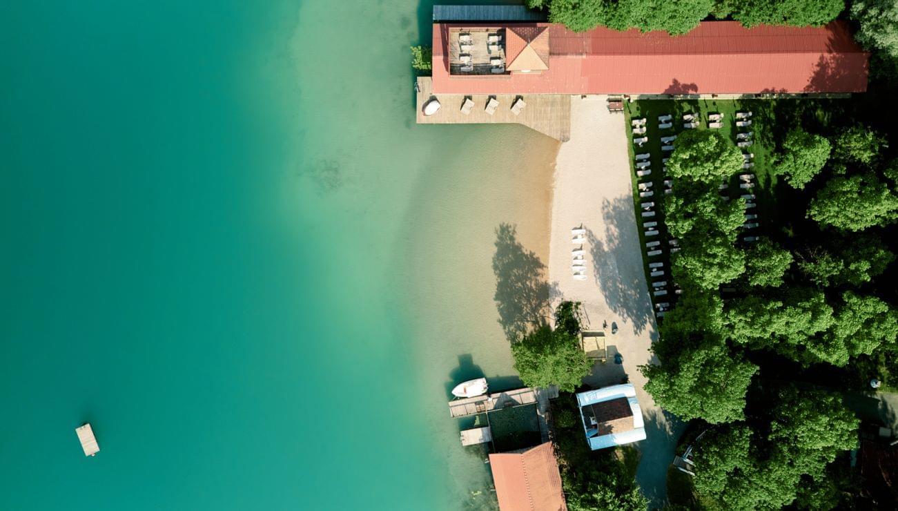 Luftaufnahme eines Seehotels mit Sonnenliegen, Sandstrand und türkisfarbenem Wasser