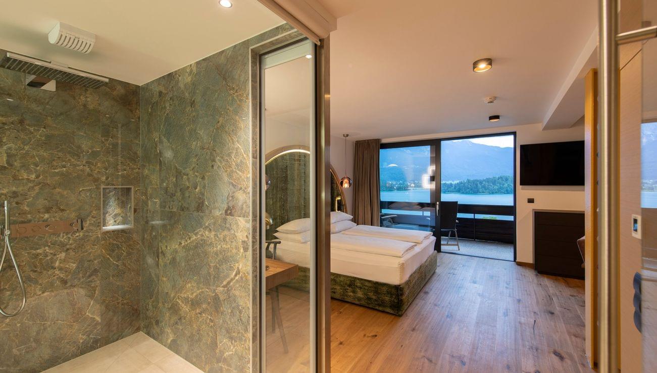 Modern hotel room with mountain view, wooden floor, open bathroom and glass shower