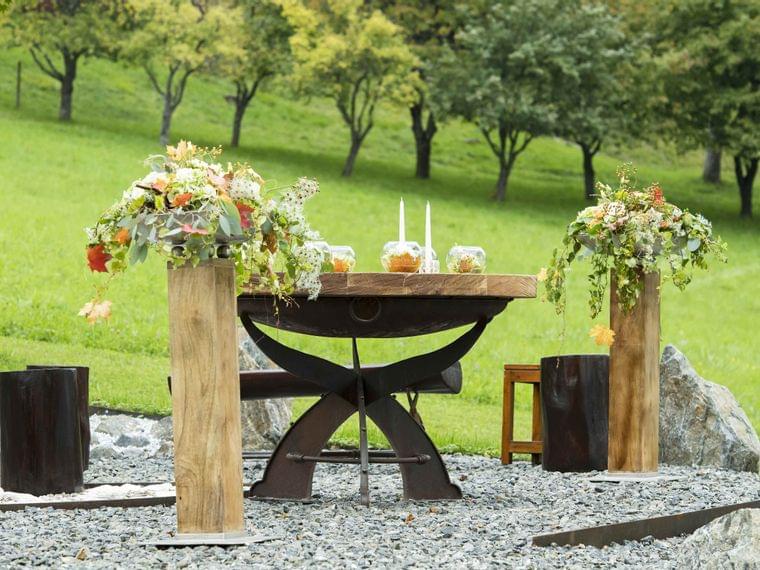 Tavolo nuziale rustico all'aperto con fiori e candele in un paesaggio verde